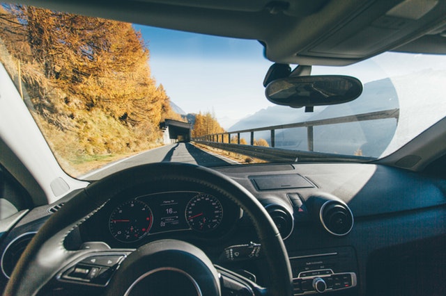 Vista en primera persona al volante de un coche que circula por una carretera con un túnel y montañas