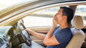 Asian young man driving a car and feel sleepy.
