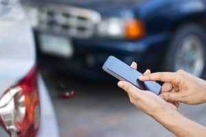 woman using smartphone at roadside after car accident