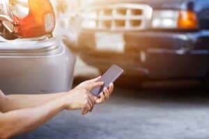 Man using smartphone at roadside after car accident