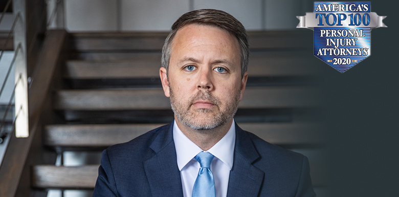 Darl Champion sitting on wood staircase wearing navy blue suit, white shirt and light blue tie.
