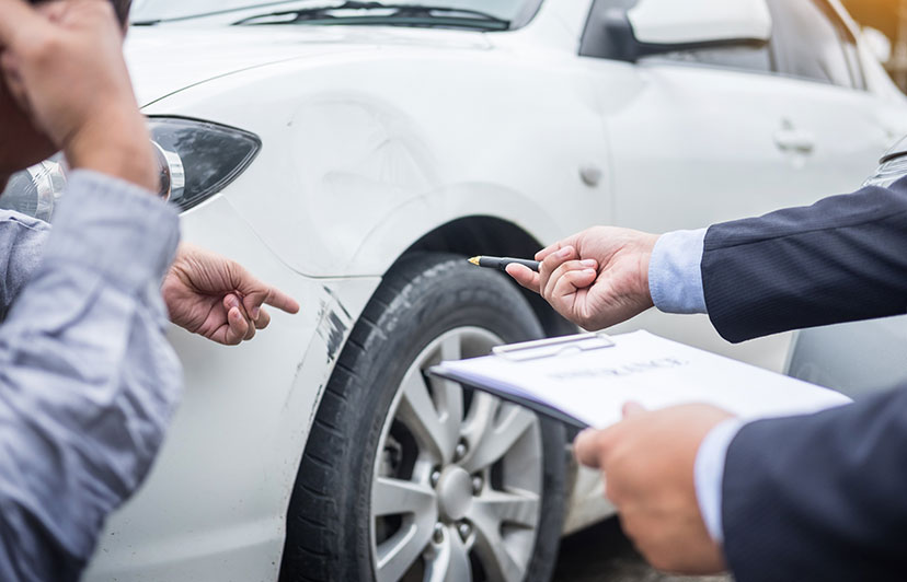 Attorney inspecting the damage in a car accident with his client