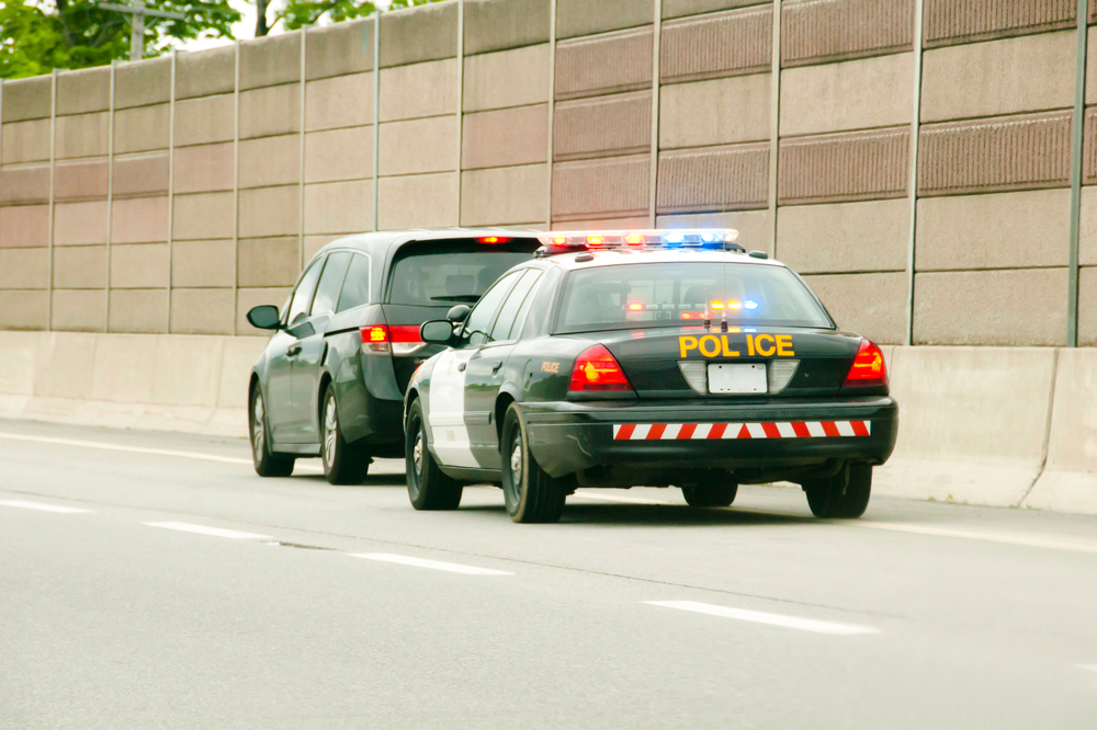 police with a car pulled over on highway shoulder