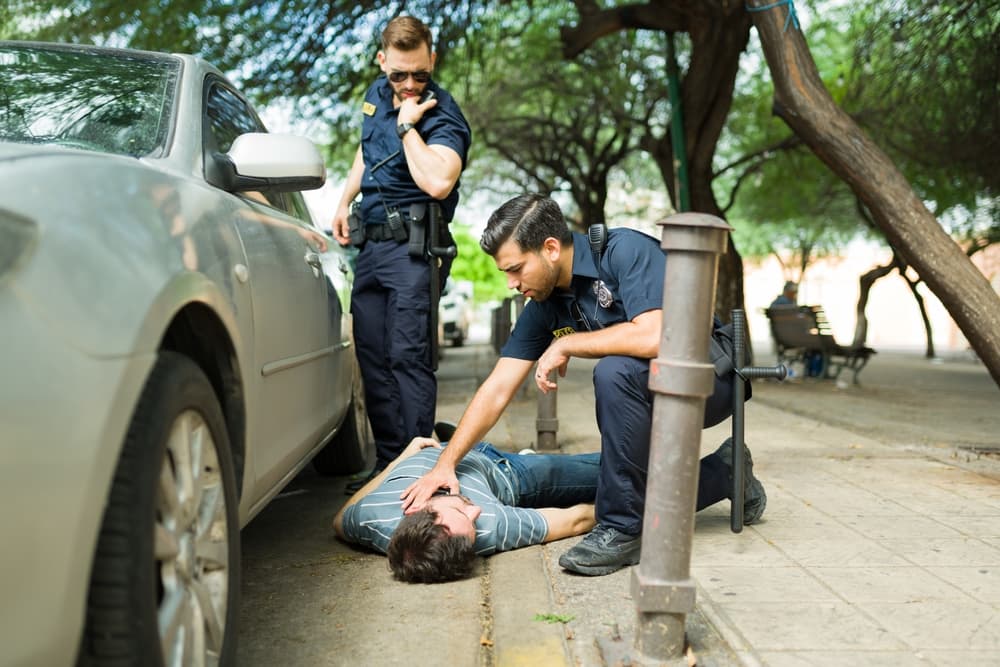 Concerned police officers attending to an injured young man involved in a car crash.