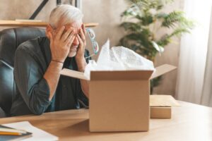 Man frustrated by damaged package. Closing his eyes in disappointment, he returns the product to the store. Unhappy online shopper facing a broken item and delivery issues.