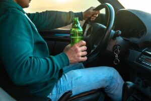 A person consumes alcohol behind the wheel, illustrating the dangers of impaired driving. Conceptualizing the risks associated with driving under the influence.