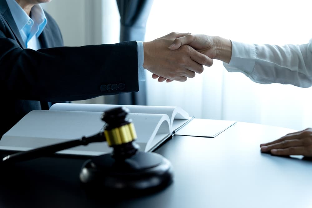 Two lawyers shaking hands in agreement, symbolizing a legal business deal or agreement in a law firm.