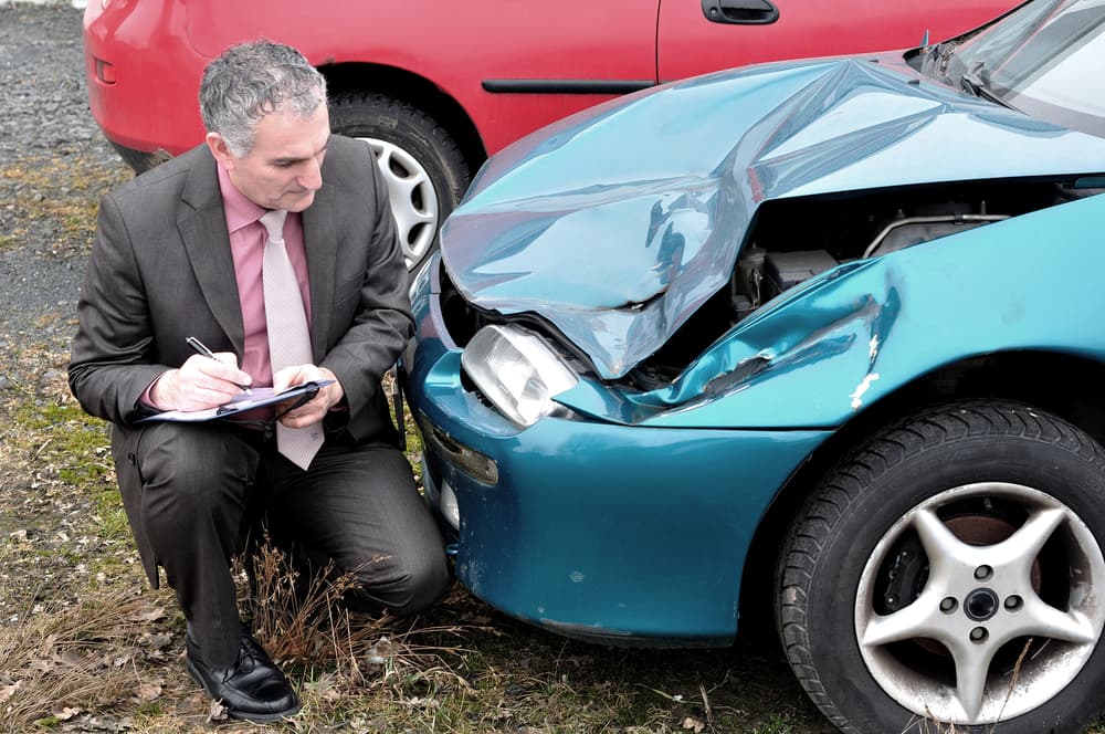 An insurance agent with damaged car