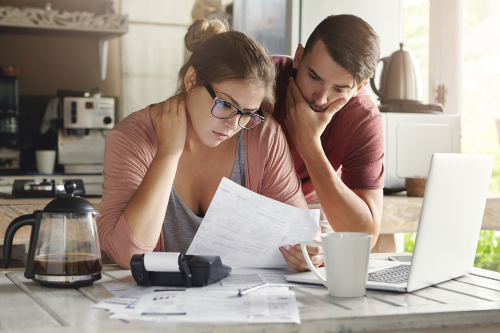Couple look at car insurance bill with worried expressions