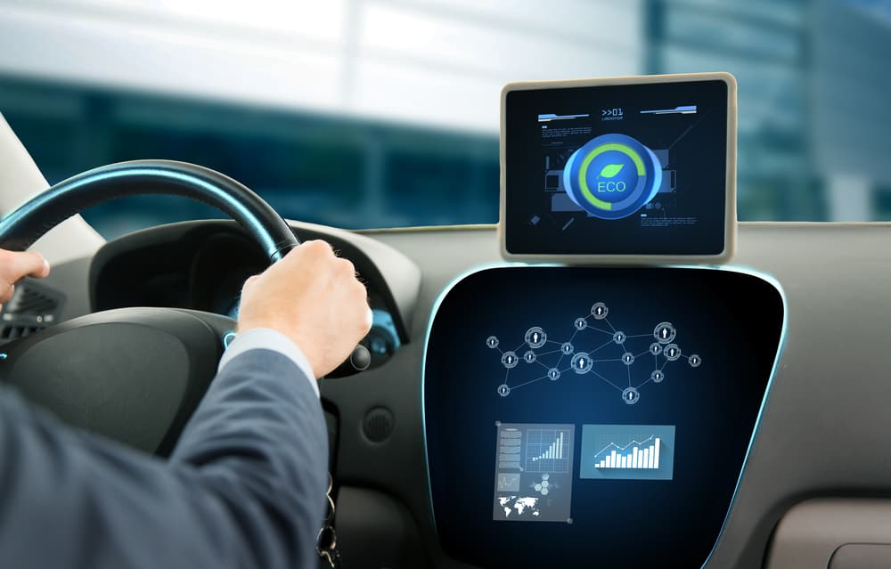Close-up of a young man driving a car and using a tablet PC, engaging the eco system mode while on a business trip.