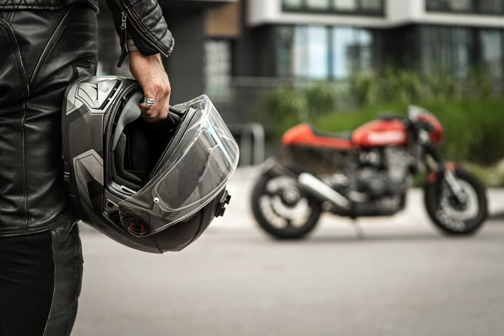 Biker walking towards motorcycle while holding helmet in hand, ready to ride