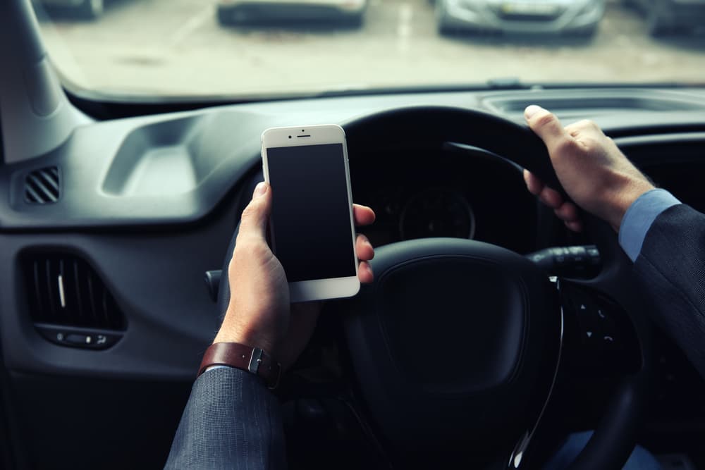 Man driver using a smartphone while sitting in his car.