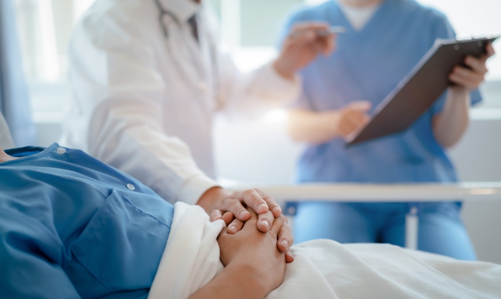 patient resting in bed while medical staff talk nearby