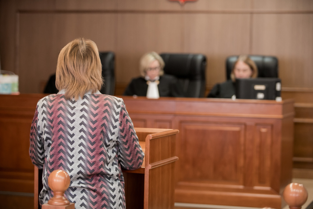 Woman in courtroom facing judge.